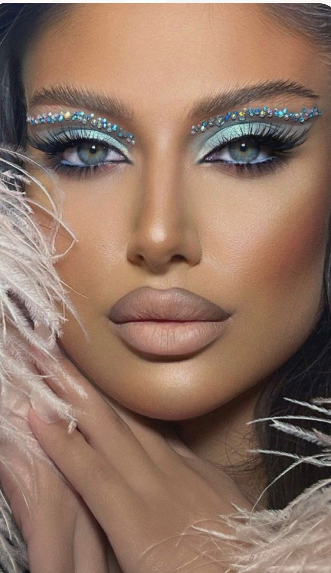 Eine Nahaufnahme des Gesichts einer Frau mit Make-up und Federn.