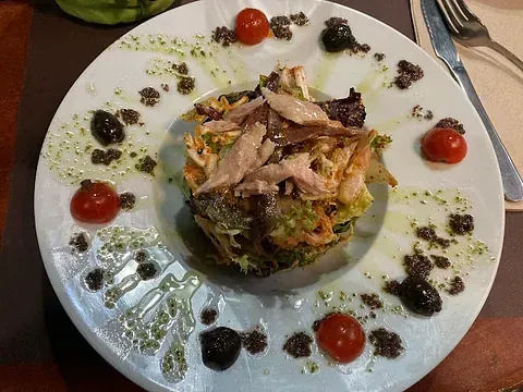 Un plato blanco cubierto con ensalada y tomates sobre una mesa.