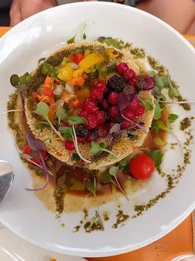 Un plato blanco cubierto con una tortilla rellena de verduras y bayas.