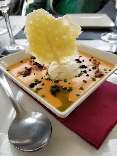 Un tazón de sopa con una cuchara dentro sobre una mesa.