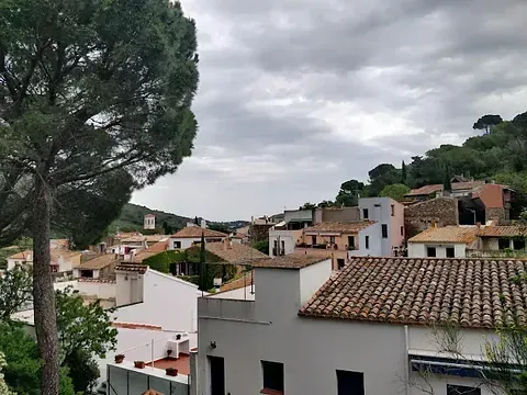 Un edificio blanco con techo de tejas está rodeado de otros edificios y árboles.