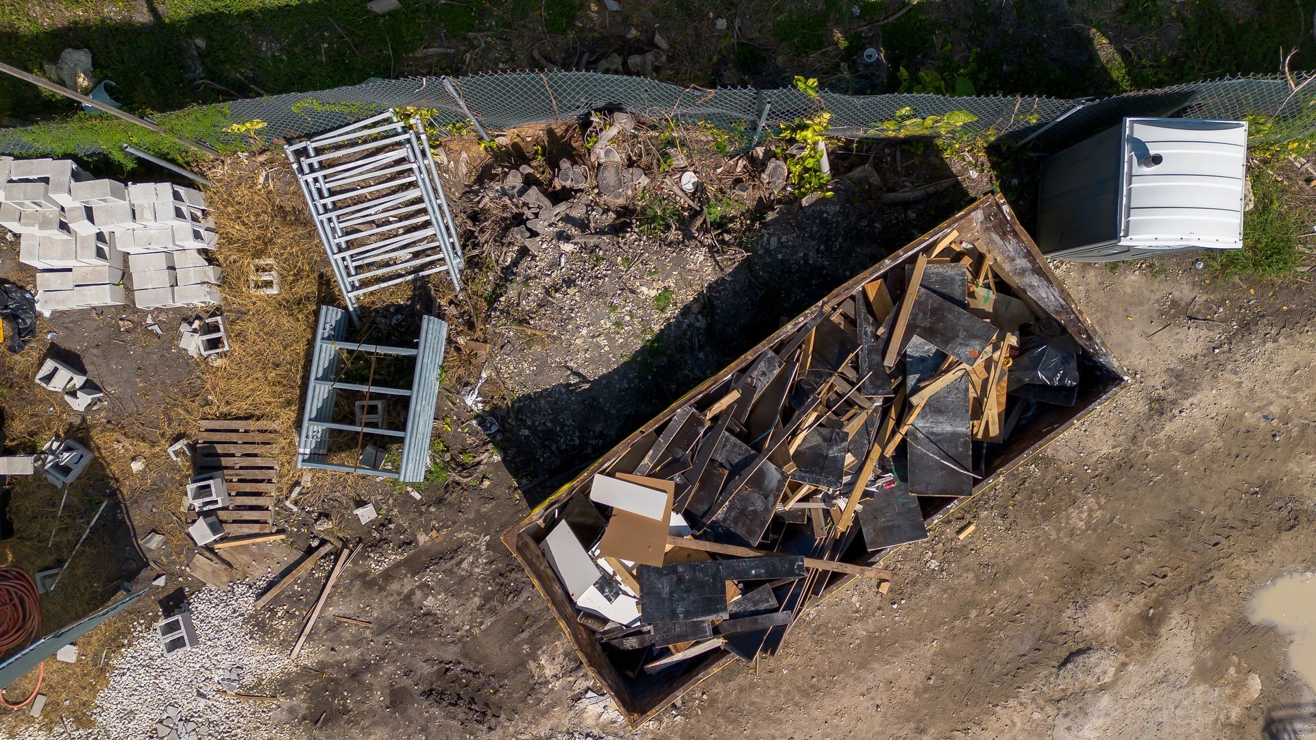 Vue aérienne de débris de construction dans une benne. Des palettes et d'autres matériaux sont également présents.