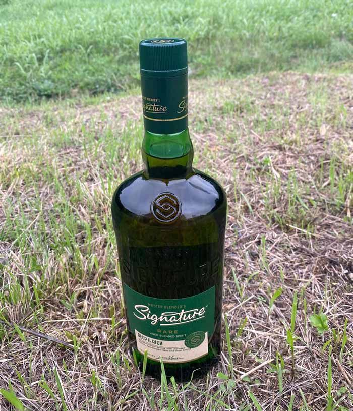 Una botella de whisky escocés de autor está en el césped.