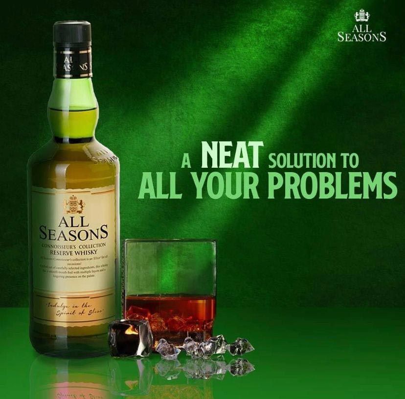 Una botella de whisky para todas las estaciones junto a un vaso de whisky.