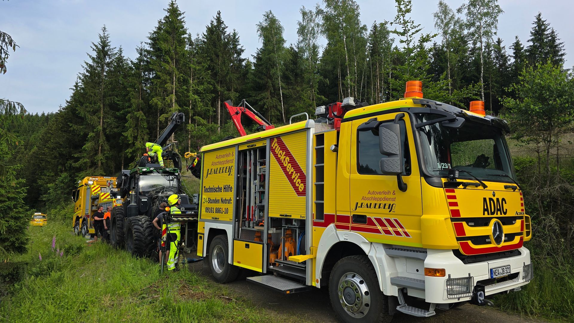 Ein gelber Abschleppwagen steht mitten in einem Wald.