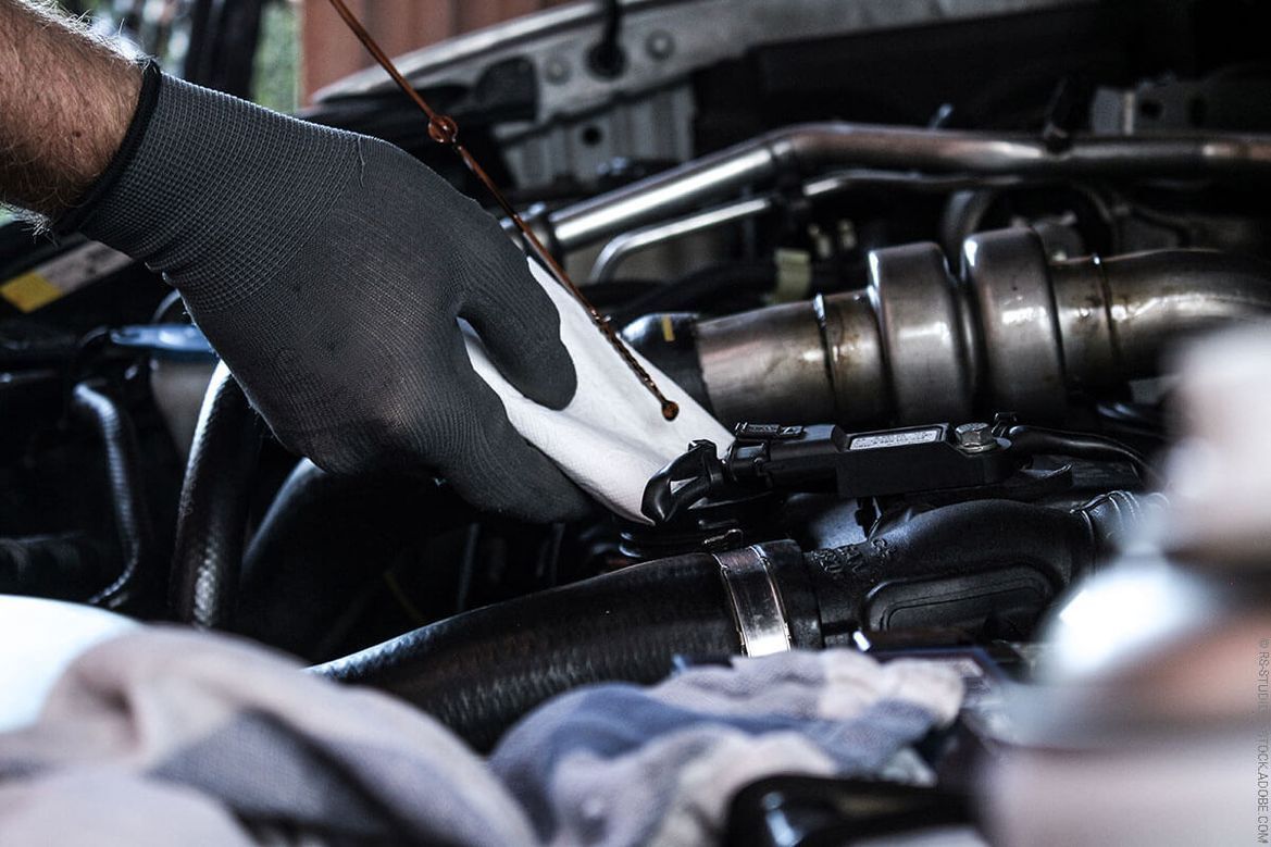 Ein Mann mit Handschuhen arbeitet an einem Automotor.