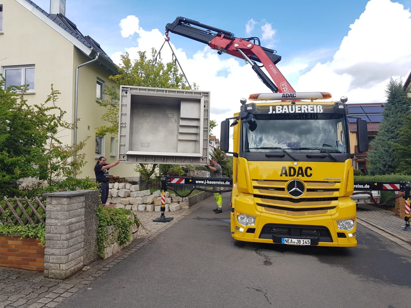 Ein gelber ADAC-LKW transportiert einen großen Container