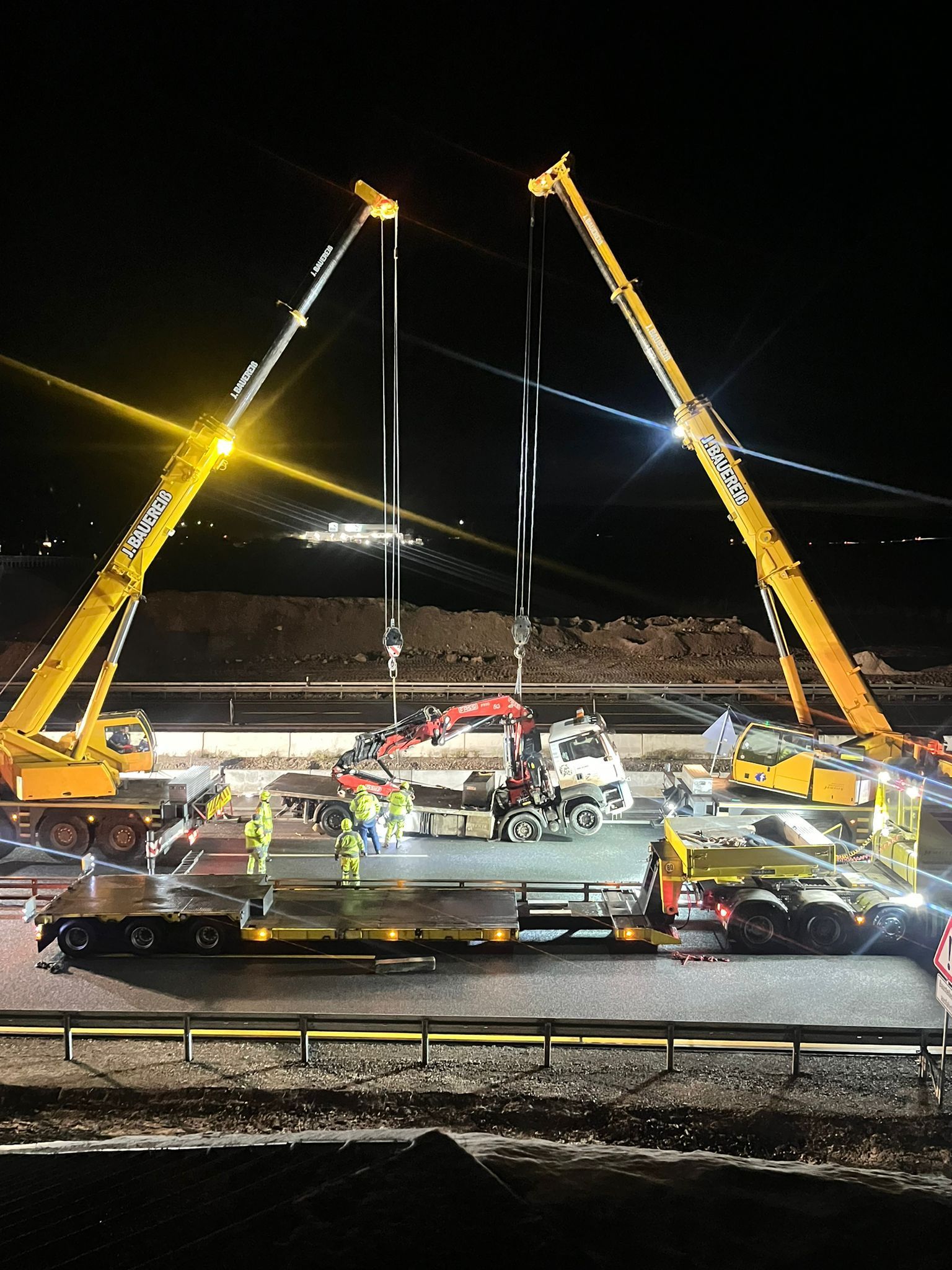 Eine Gruppe Bauarbeiter arbeitet nachts an einer Brücke.