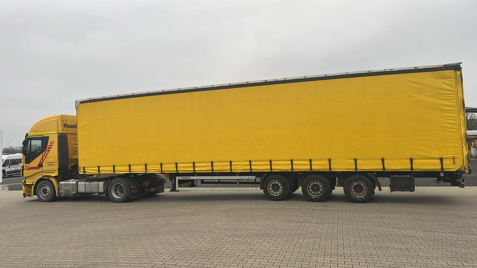 Ein gelber Sattelschlepper parkt auf einem Feldweg.
