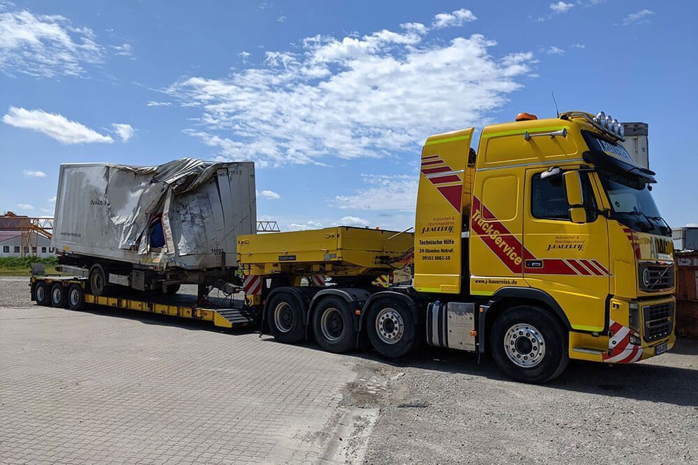 Ein gelber Sattelschlepper transportiert einen großen Betonblock.