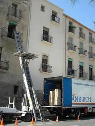 Un camión azul con la palabra Ambrich en el costado está estacionado frente a un edificio.