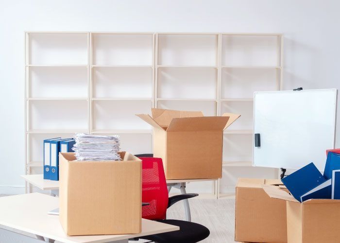 Una oficina en movimiento con cajas en los escritorios y sillas.