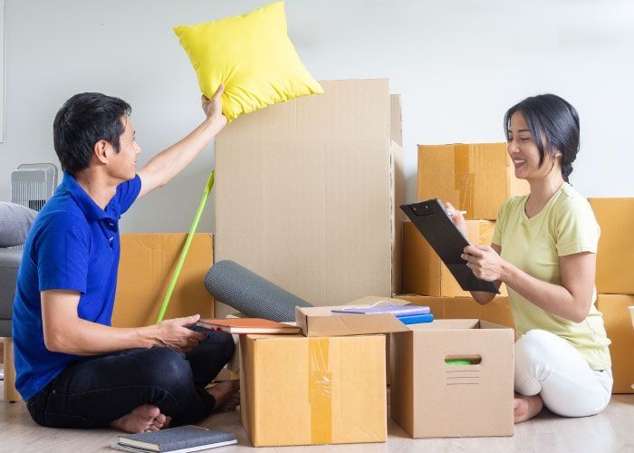 Un hombre sostiene una almohada amarilla mientras una mujer mira un portapapeles.