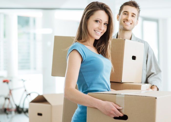 Un hombre y una mujer sostienen cajas de cartón y sonríen.