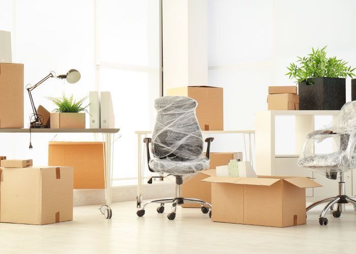 Una oficina con cajas y una silla envuelta en plástico.