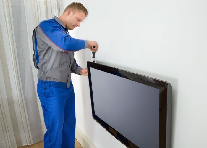 Un hombre está instalando un televisor de pantalla plana en una pared.