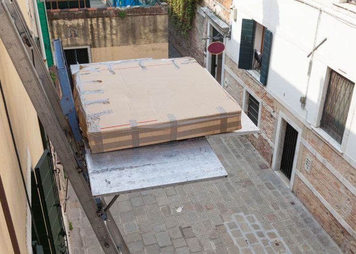 Se levanta un gran trozo de cartón mediante una escalera.