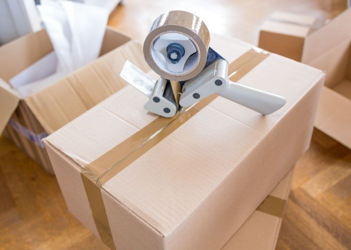 Un dispensador de cinta está colocado encima de una caja de cartón.