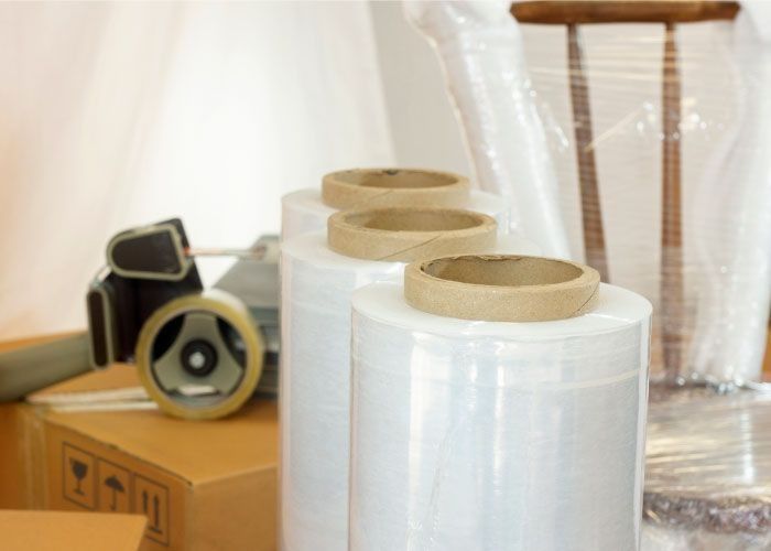 Tres rollos de envoltura de plástico están colocados encima de una caja de cartón.