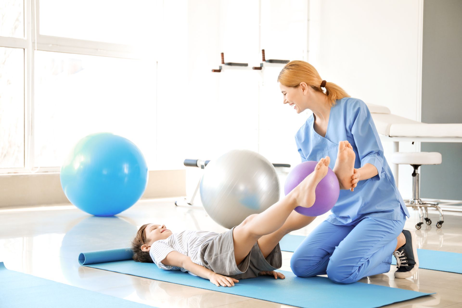 Eine Frau kniet neben einem Kind auf einer Yogamatte.