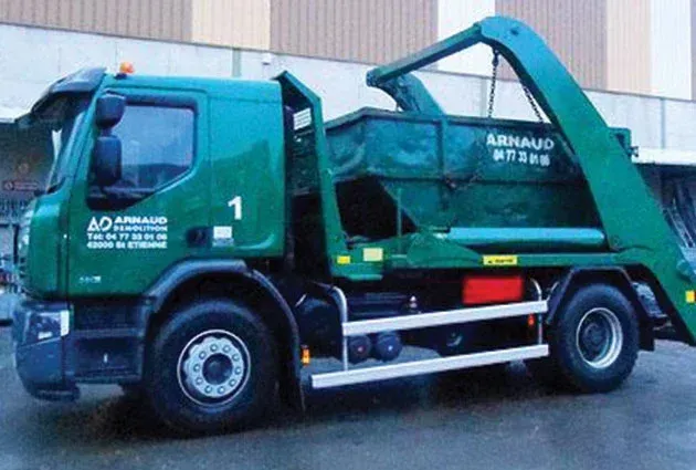 Camion de collecte des déchets verts avec conteneur, stationné à l'extérieur.