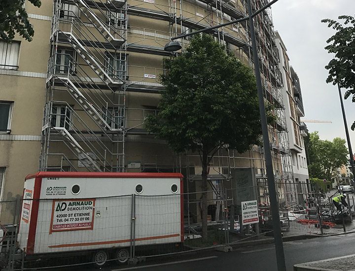 Façade d'un bâtiment en cours de rénovation avec échafaudages et unité de construction mobile.