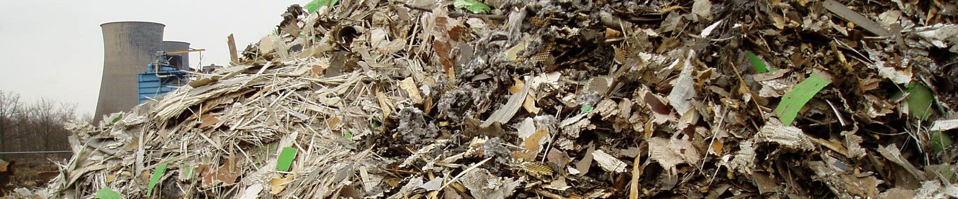 Tas de déchets industriels avec une structure en arrière-plan. Les tons verts et bruns dominent.