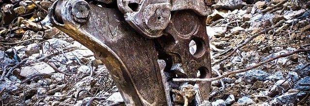 Gros plan sur une griffe métallique au milieu de débris, probablement du matériel de démolition.