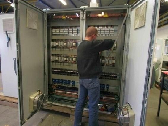 Personne travaillant à l'intérieur d'une armoire électrique ouverte