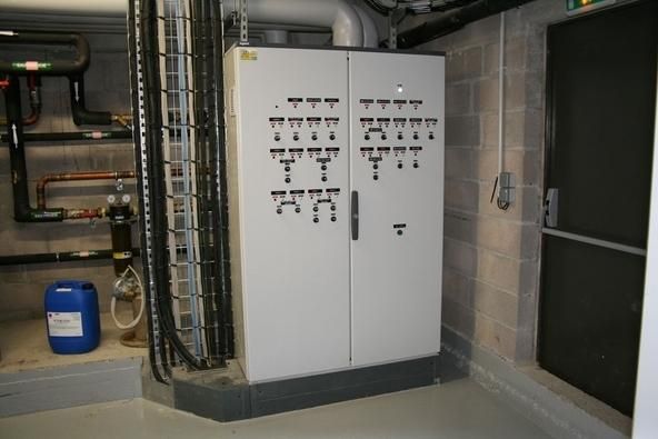 Armoire électrique industrielle dans un local technique avec tuyauterie et murs en béton
