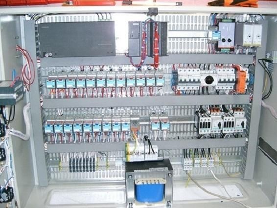 Armoire de commande électrique avec câblage, relais, disjoncteurs et un composant bleu monté à l'intérieur.
