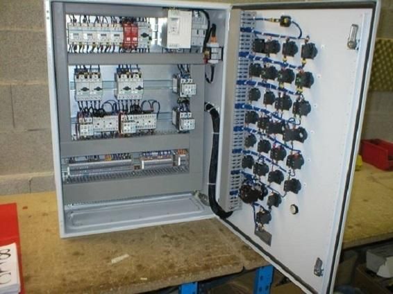Panneau de commande électrique ouvert avec câblage et relais dans une armoire grise