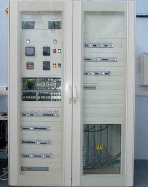 Armoire électrique ouverte avec interrupteurs, relais et panneaux de câblage, boîtier métallique blanc.