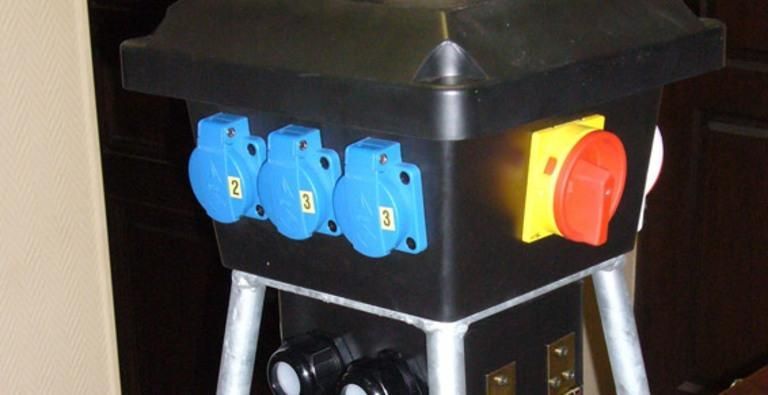 Des prises électriques bleues et un interrupteur rouge sur le côté d'une machine noire.