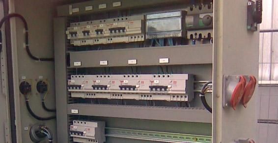 Panneau de commande électrique ouvert avec disjoncteurs, câblage et interrupteur rotatif rouge