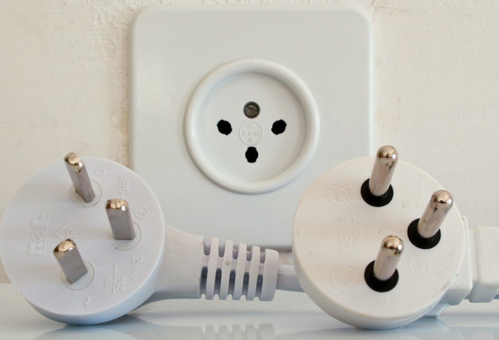 Deux prises électriques blanches dans une prise murale, une à 3 broches et une à 2 broches, avec un cordon blanc en dessous.