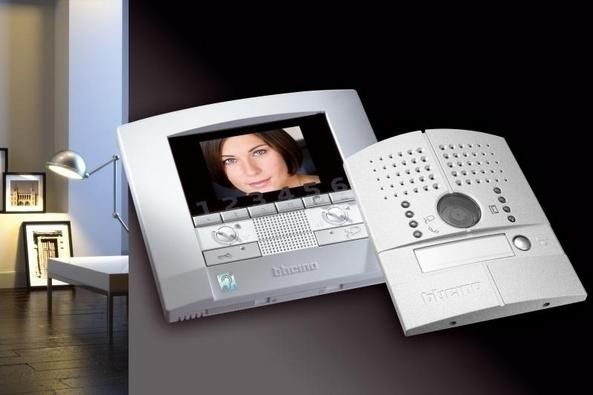 Combiné d'interphone vidéo moderne avec écran affichant le visage d'une femme, design argenté et blanc sur une table