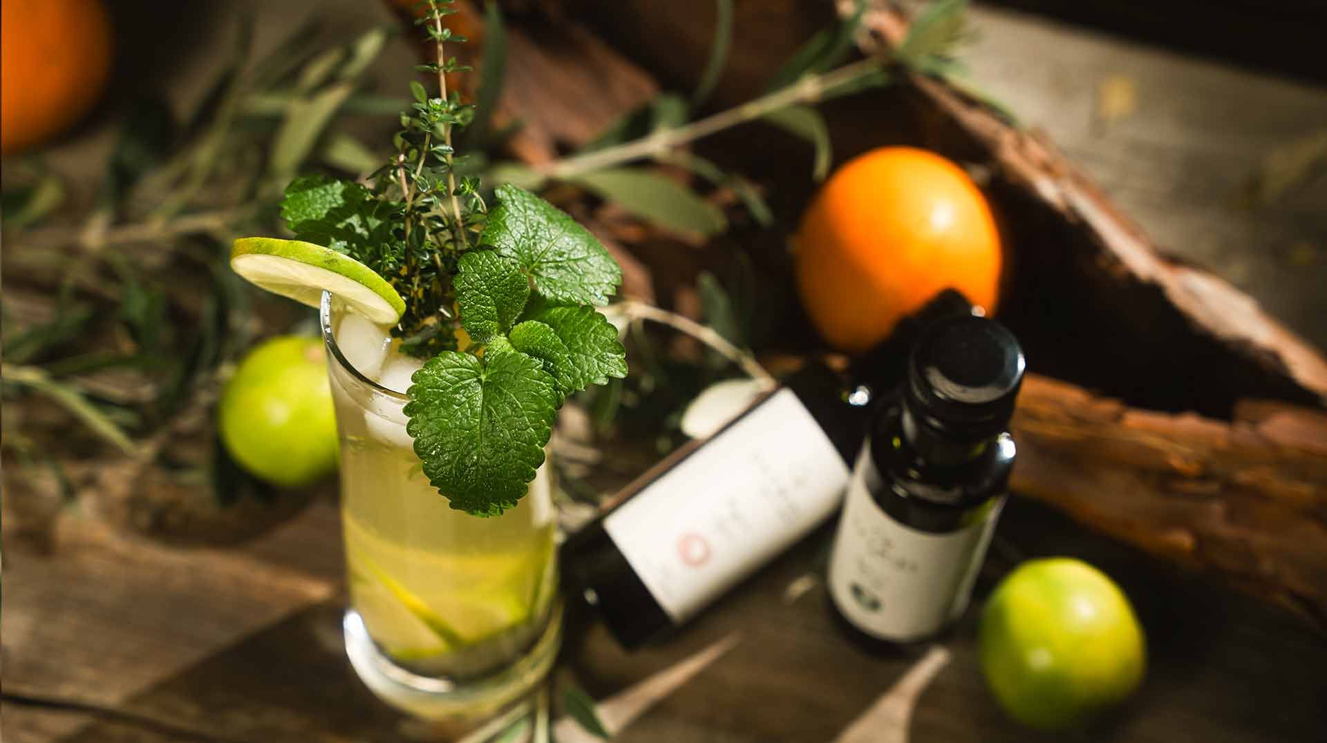 Cocktail with mint and lime beside bottles and citrus on a rustic table