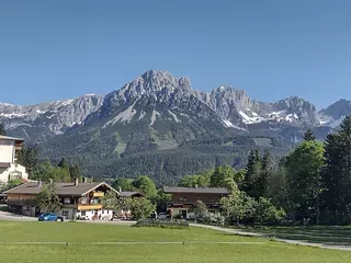 Ein Haus mitten auf einem Feld mit Bergen im Hintergrund.