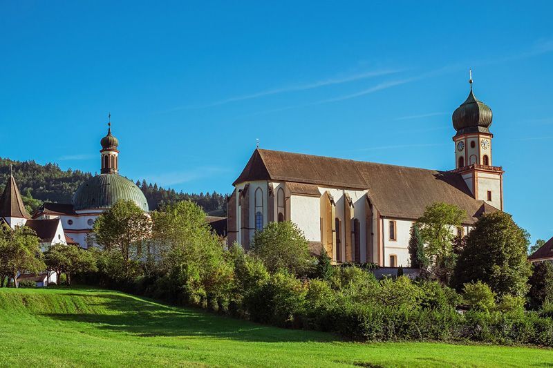 Kirchenanlage mit grünem Gras im Vordergrund und blauem Himmel im Hintergrund.