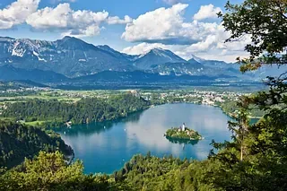 Ein See mit einer kleinen Insel in der Mitte und Bergen im Hintergrund.