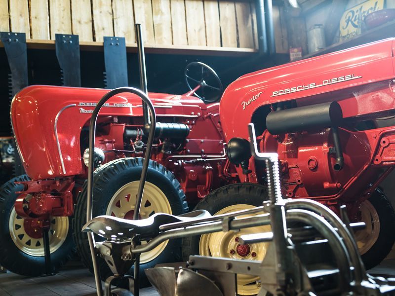 Zwei rote Porsche-Dieseltraktoren parkten in einem Holzgebäude.
