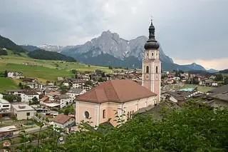 Eine Kirche mitten in einem Dorf mit Bergen im Hintergrund