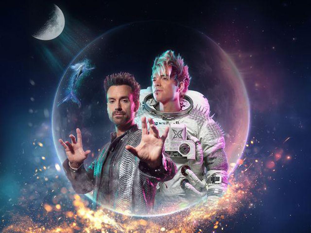 Die Ehrlich Brothers, einer davon in einem Raumanzug, stehen in einer leuchtenden kosmischen Kugel vor einem dunklen Sternenhintergrund mit einer Mondsichel.