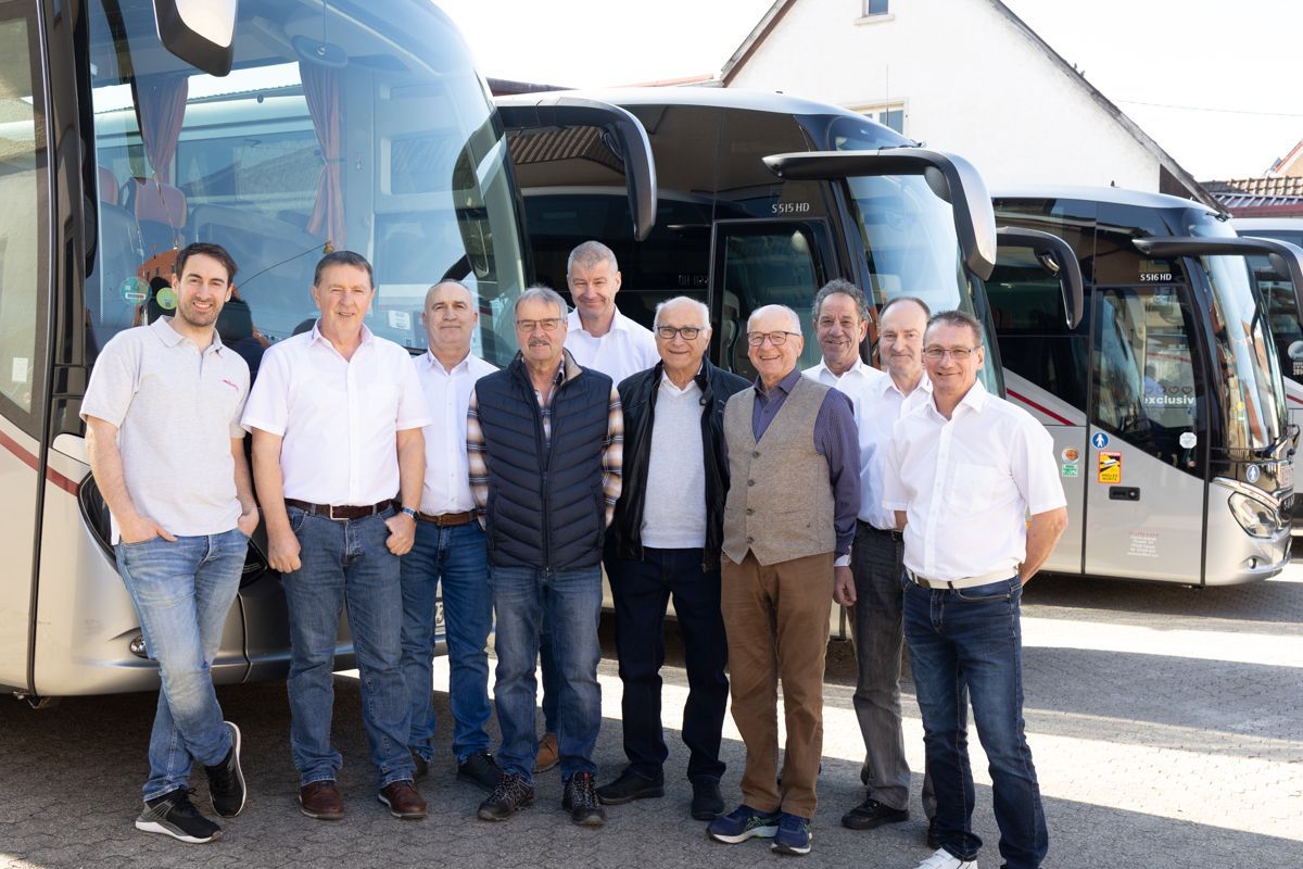 Eine Gruppe Männer posiert vor einem Bus für ein Foto.