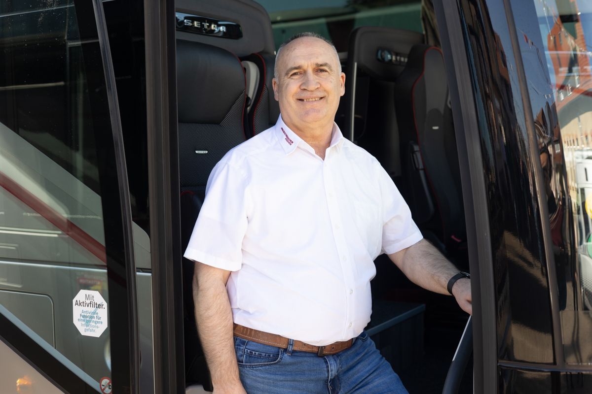 Ein Mann in einem weißen Hemd steht in der Tür eines Busses