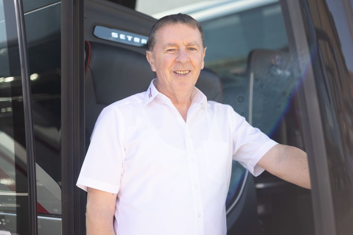 Ein Mann in einem weißen Hemd steht in der Tür eines Busses