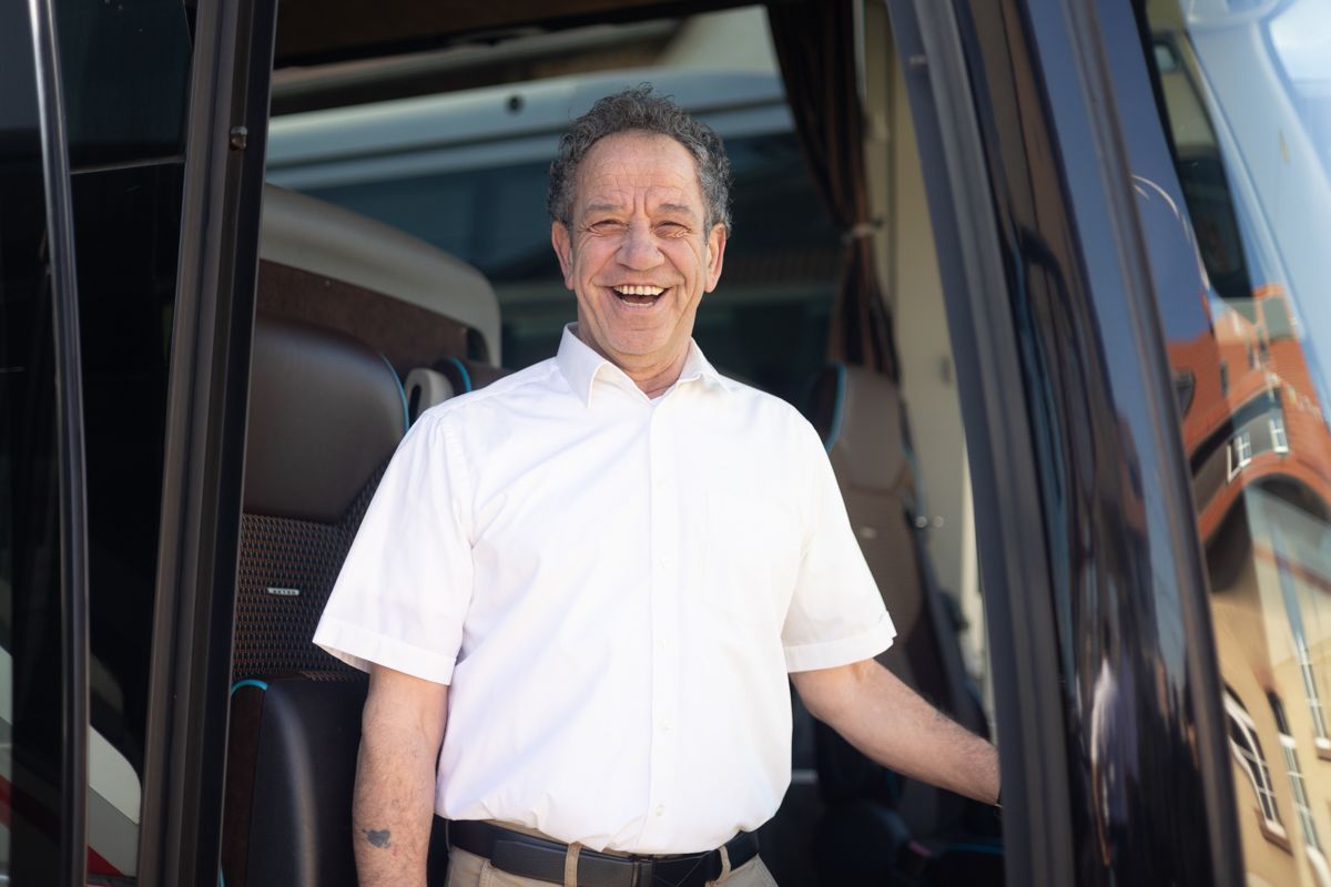Ein Mann in einem weißen Hemd steht im Türrahmen eines Busses.