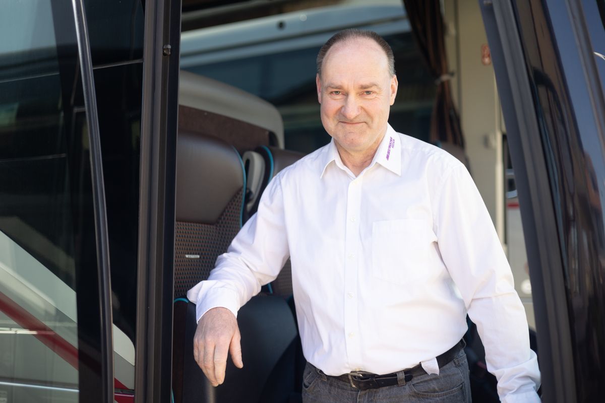 Ein Mann in einem weißen Hemd steht im Türrahmen eines Busses.