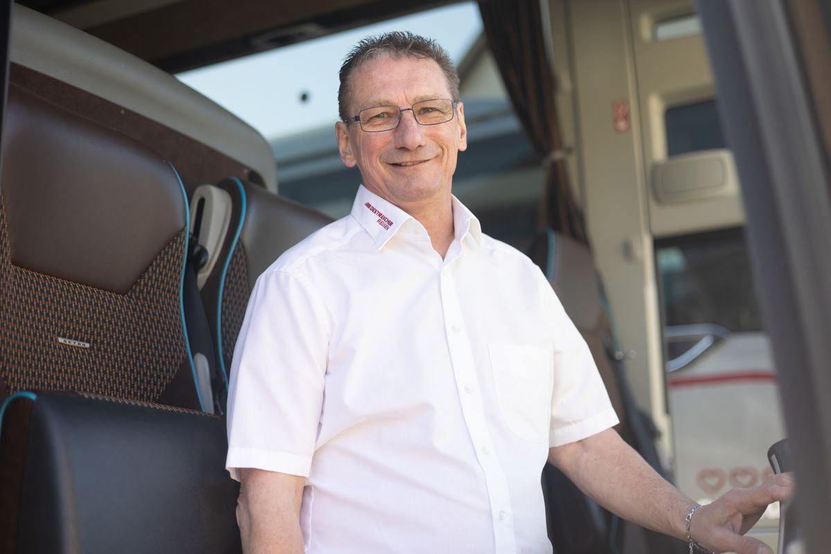 Ein Mann in einem weißen Hemd steht im Türrahmen eines Busses.